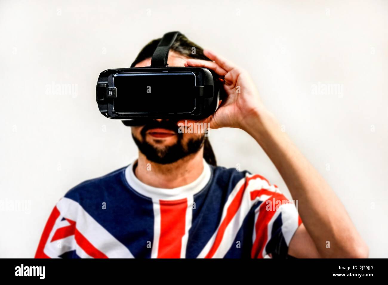 Homme sur fond blanc avec micro-casques de réalité virtuelle en marche, testant la nouvelle technologie VR. Homme avec 4K verres regardant des jeux ou des vidéos Banque D'Images