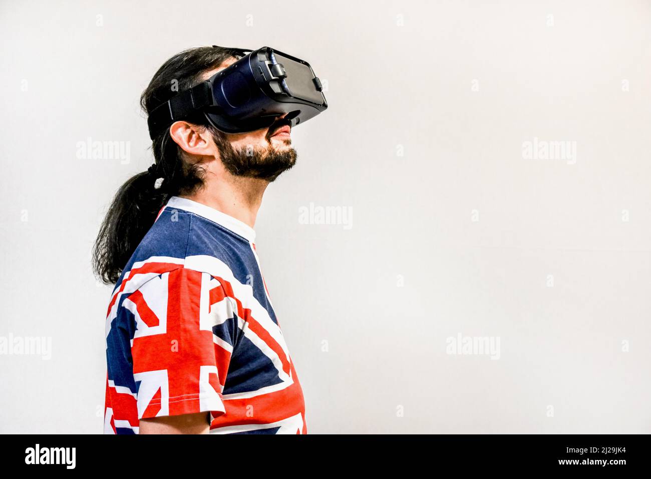 Homme sur fond blanc avec micro-casques de réalité virtuelle en marche, testant la nouvelle technologie VR. Homme avec 4K verres regardant des jeux ou des vidéos Banque D'Images