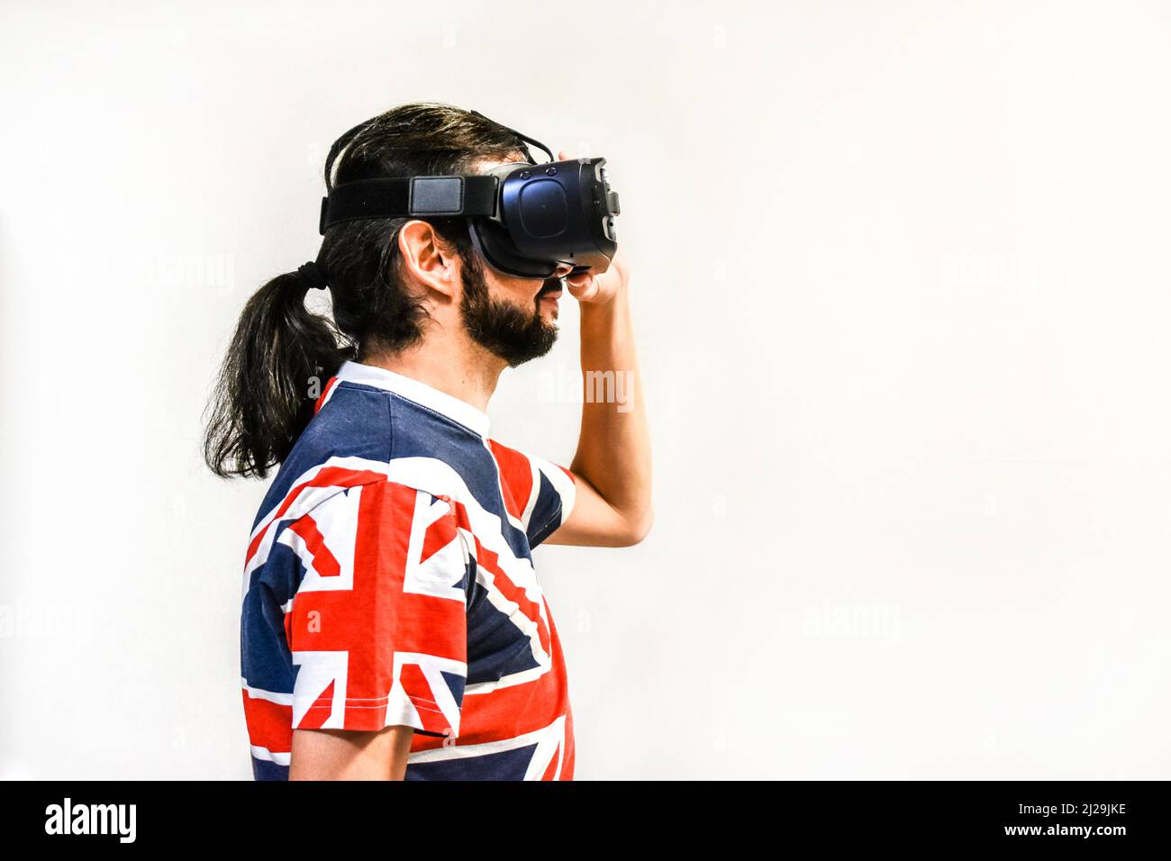 Homme sur fond blanc avec micro-casques de réalité virtuelle en marche, testant la nouvelle technologie VR. Homme avec 4K verres regardant des jeux ou des vidéos Banque D'Images