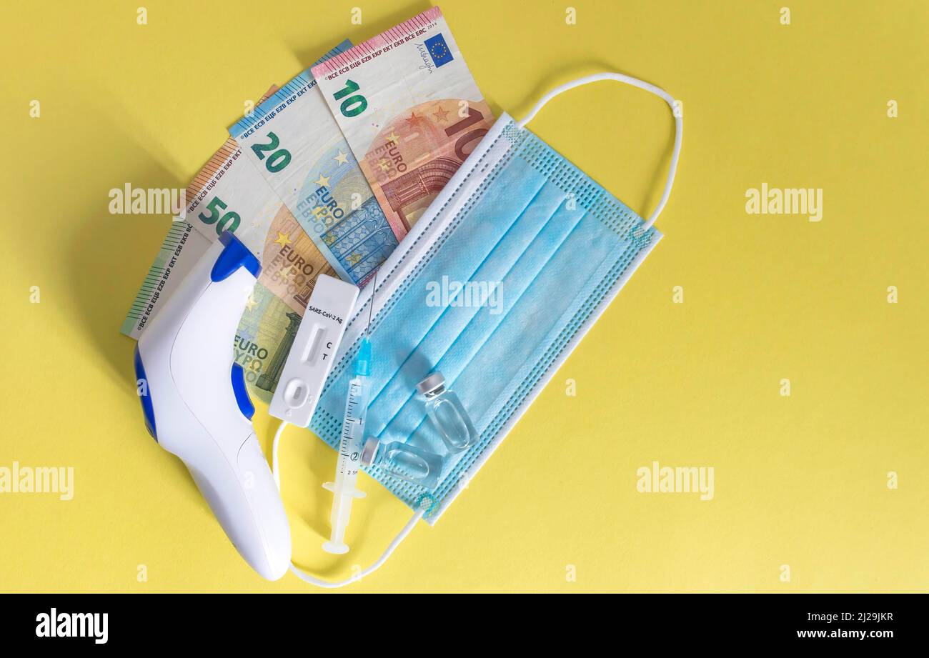 Argent (billets en euros) avec masques médicaux, test d'antigène, flacons de vaccin et seringue. Crise financière due aux pertes du coronavirus, attention sélective Banque D'Images