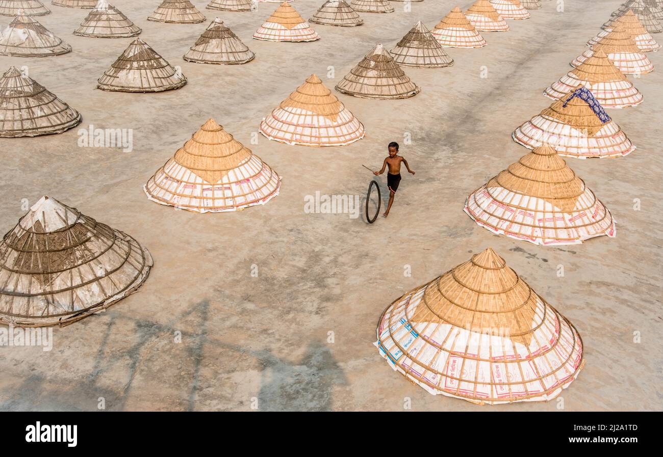 Brahmanbaria, Chittagong, Bangladesh. 31st mars 2022. Les enfants courent et jouent parmi des centaines de moulins à riz traditionnels faits de bambou.après avoir été bouilli, le grain est balayé en tas par les travailleurs et séché jusqu'à huit heures à Brahmanbaria, au Bangladesh. Le travailleur du moulin à riz a commencé son travail dès le début de la matinée, de 5 heures à 2pm heures tous les jours. Après la période du déjeuner, les enfants des travailleurs jouent leurs jeux de l'après-midi avec des amis dans ce champ de moulin à riz. (Credit image: © Mustasinur Rahman Alvi/ZUMA Press Wire) Credit: ZUMA Press, Inc./Alamy Live News Banque D'Images