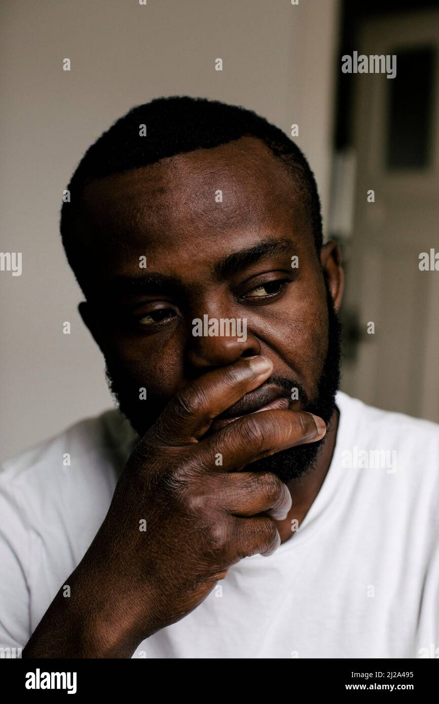 Homme mentalement malade avec la main sur le menton regardant loin à la maison Banque D'Images