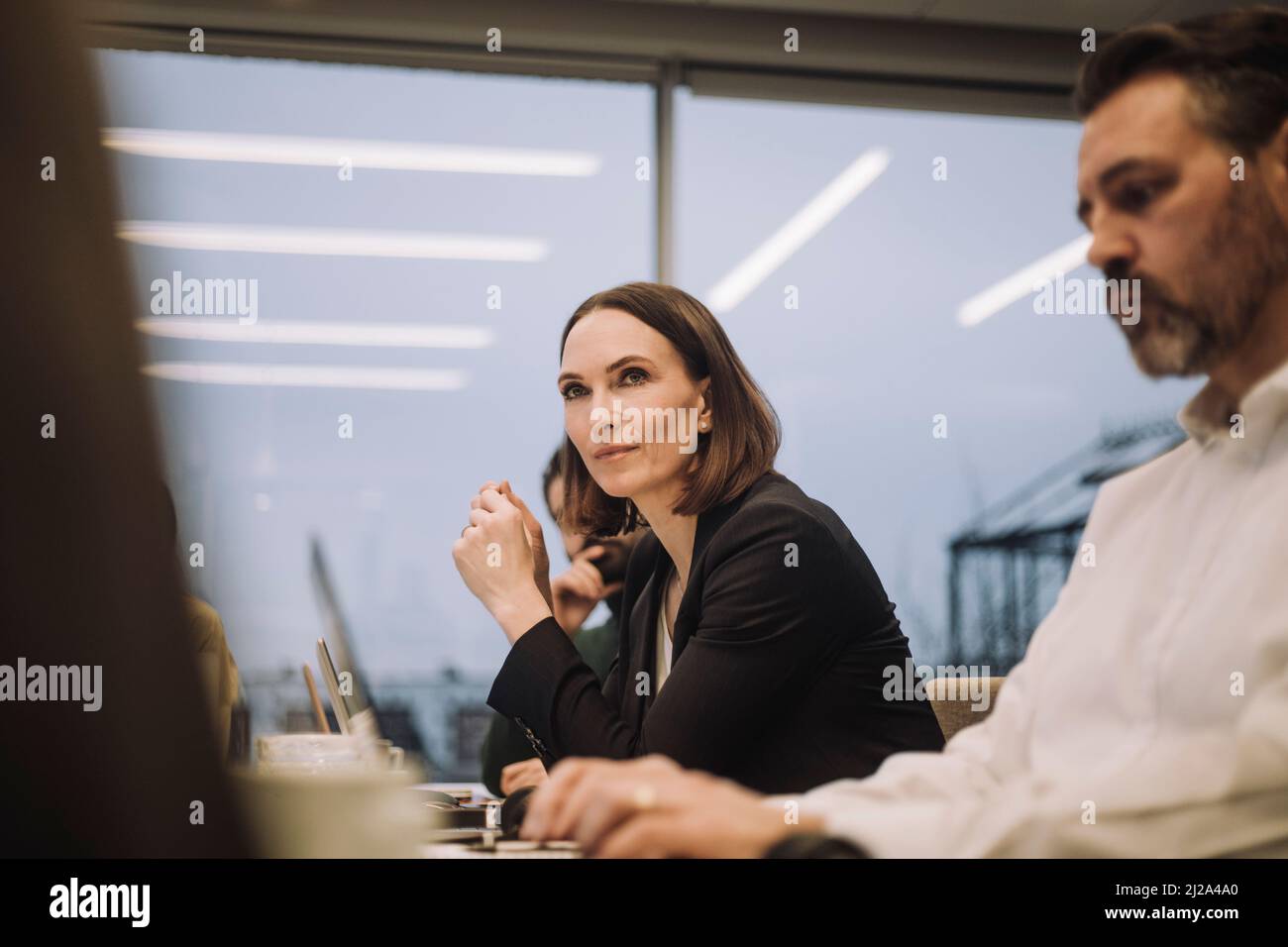 Femme d'affaires confiante et mûre discutant avec ses collègues au bureau Banque D'Images