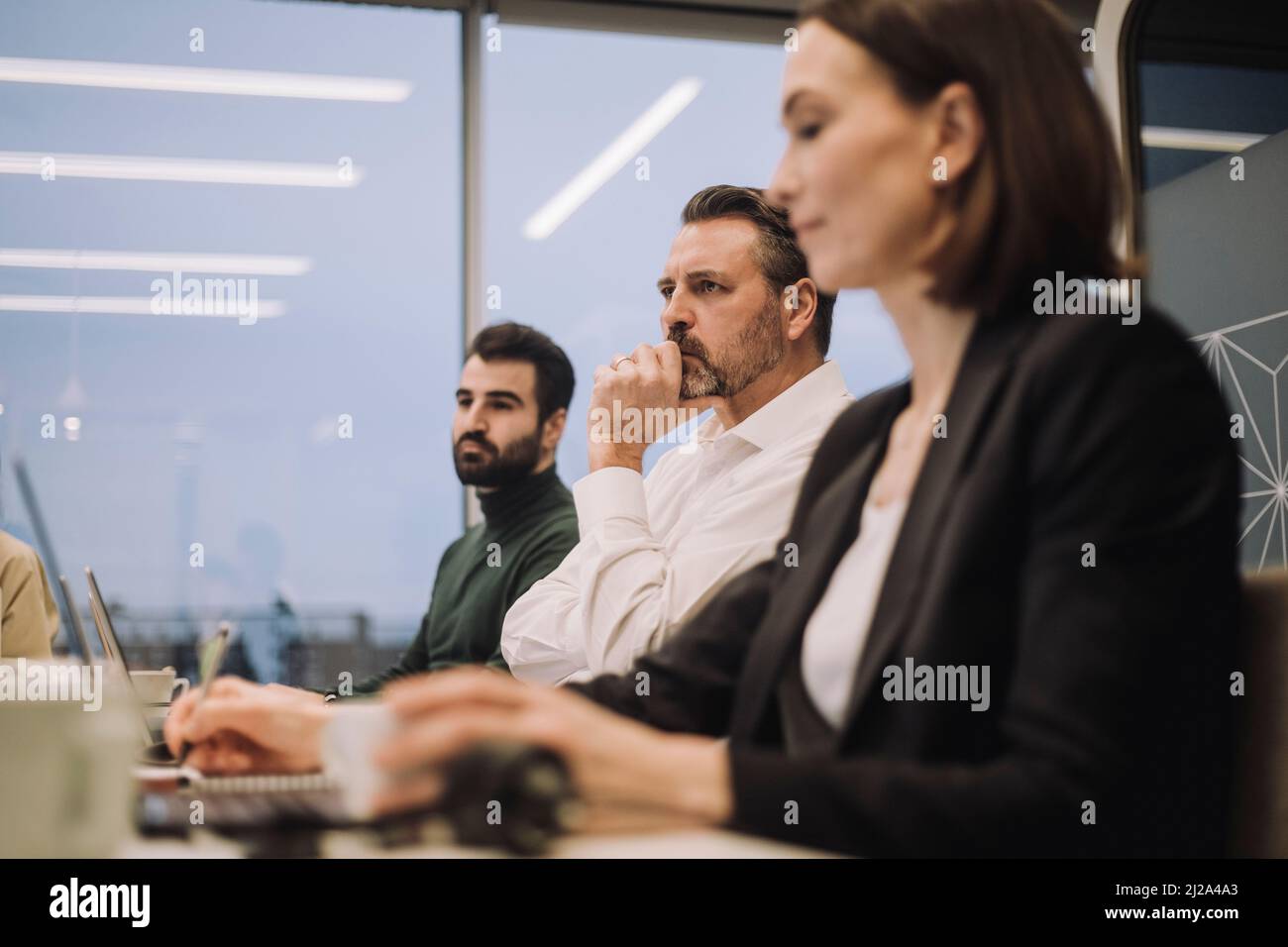 Homme d'affaires dévoué avec des collègues hommes et femmes discutant en réunion sur le lieu de travail Banque D'Images