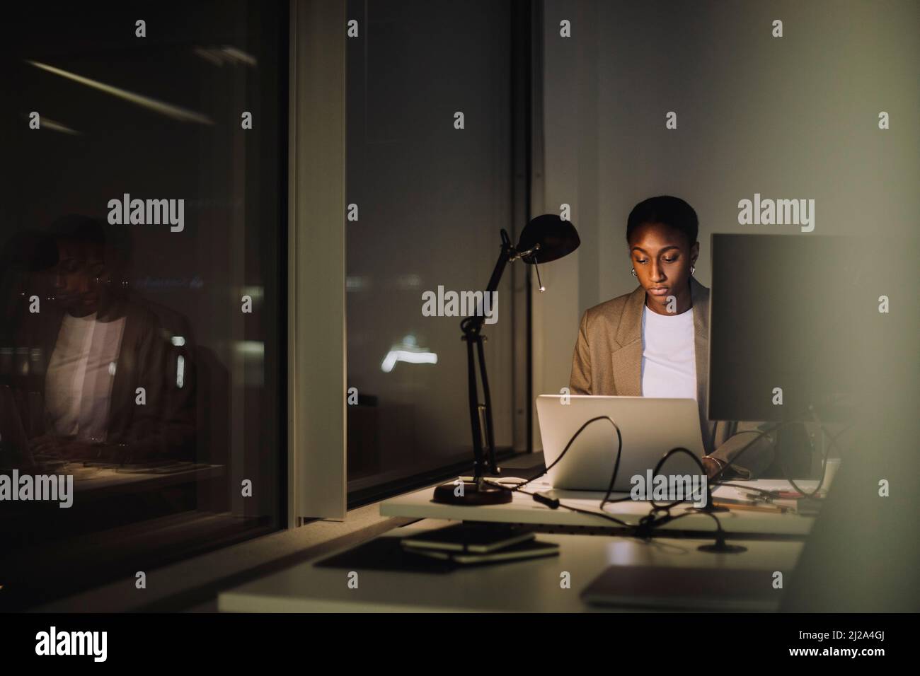 Femme d'affaires ambitieuse utilisant un ordinateur portable tout en travaillant à la dernière minute au bureau Banque D'Images