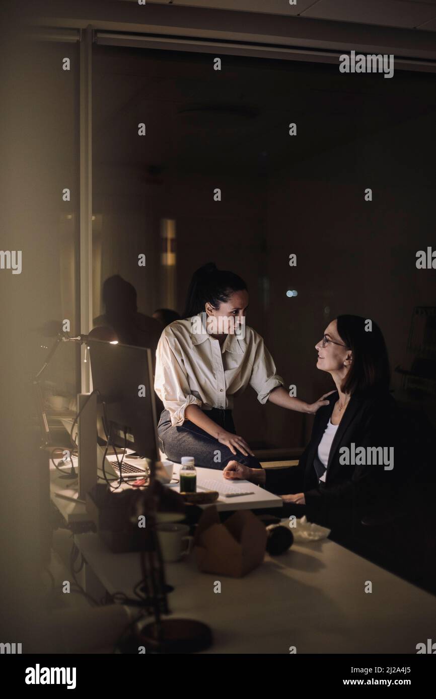Une femme d'affaires planifie une stratégie avec une collègue féminine alors qu'elle travaille à la dernière minute au bureau Banque D'Images