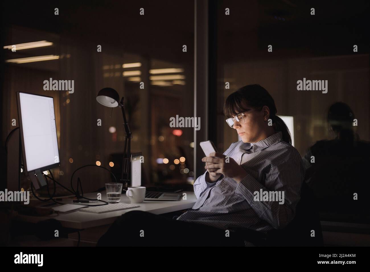 Messagerie texte femme d'affaires sur smartphone assis au travail Banque D'Images