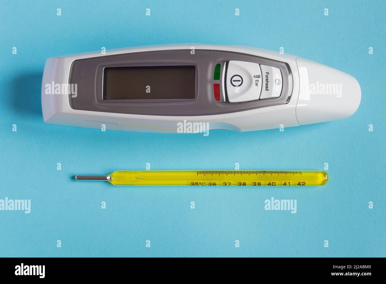 Deux thermomètres de différentes époques, un mercure et un avec affichage LED et technologie laser sur un fond texturé coloré. Voiture de santé Banque D'Images
