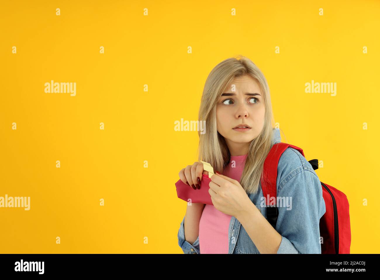 Fille étudiante avec feuille de triche sur fond jaune Banque D'Images