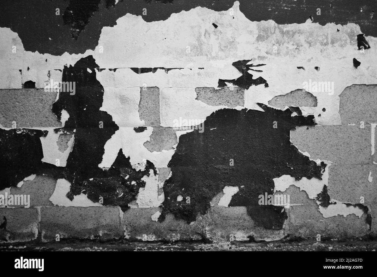 Un mur industriel négligé et abandonné avec des couches de peinture qui s'écaillent de lui en noir et blanc. Banque D'Images