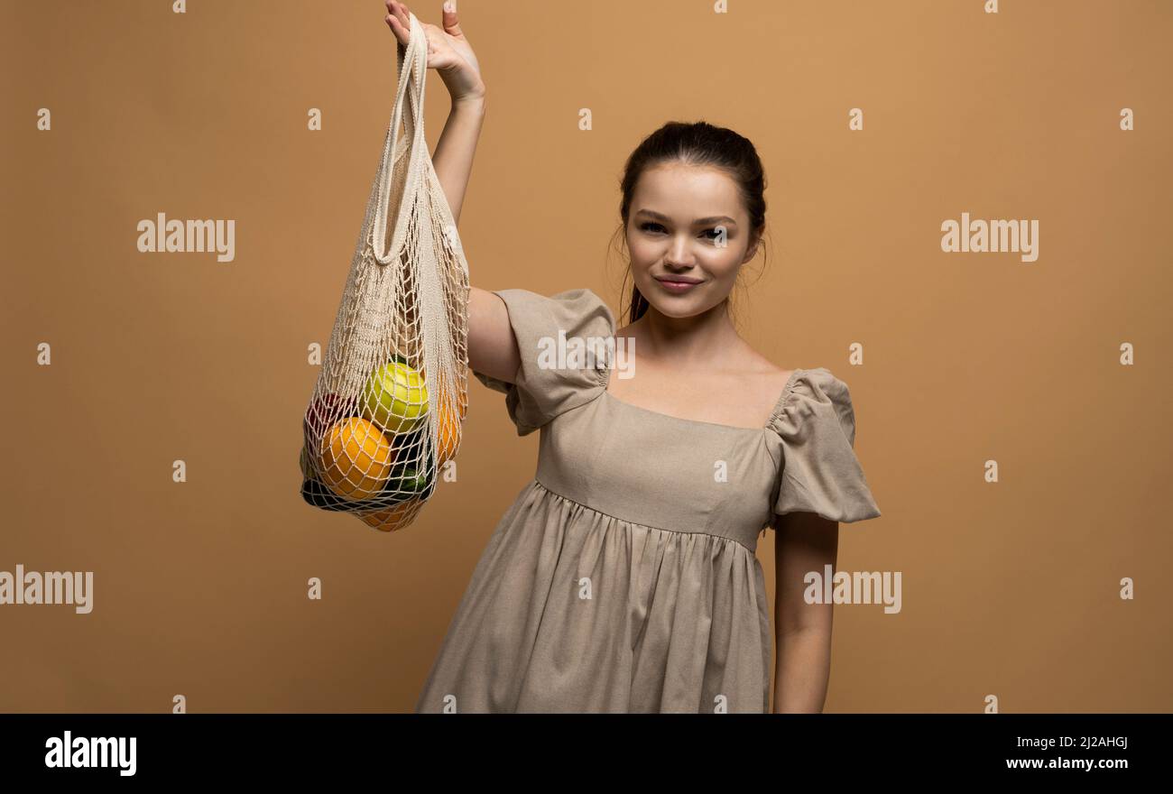 Concept sans déchets, sans plastique.Jeune femme brune avec sac en maille de coton réutilisable avec fruits et légumes.Shopping sans emballage plastique Banque D'Images