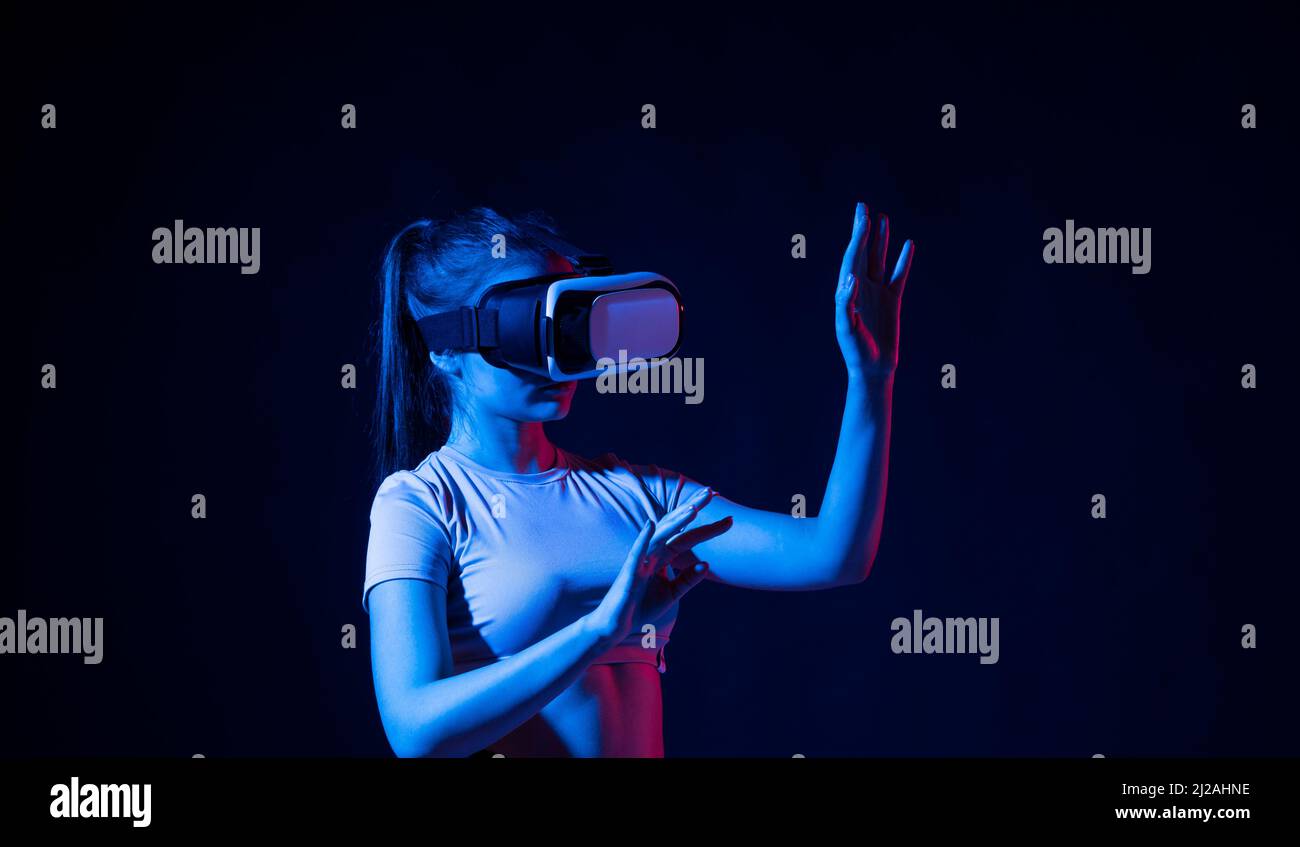 Portrait d'une femme avec un casque de réalité virtuelle et des gestes avec les mains, elle utilise la technologie VR pour le design industriel Banque D'Images