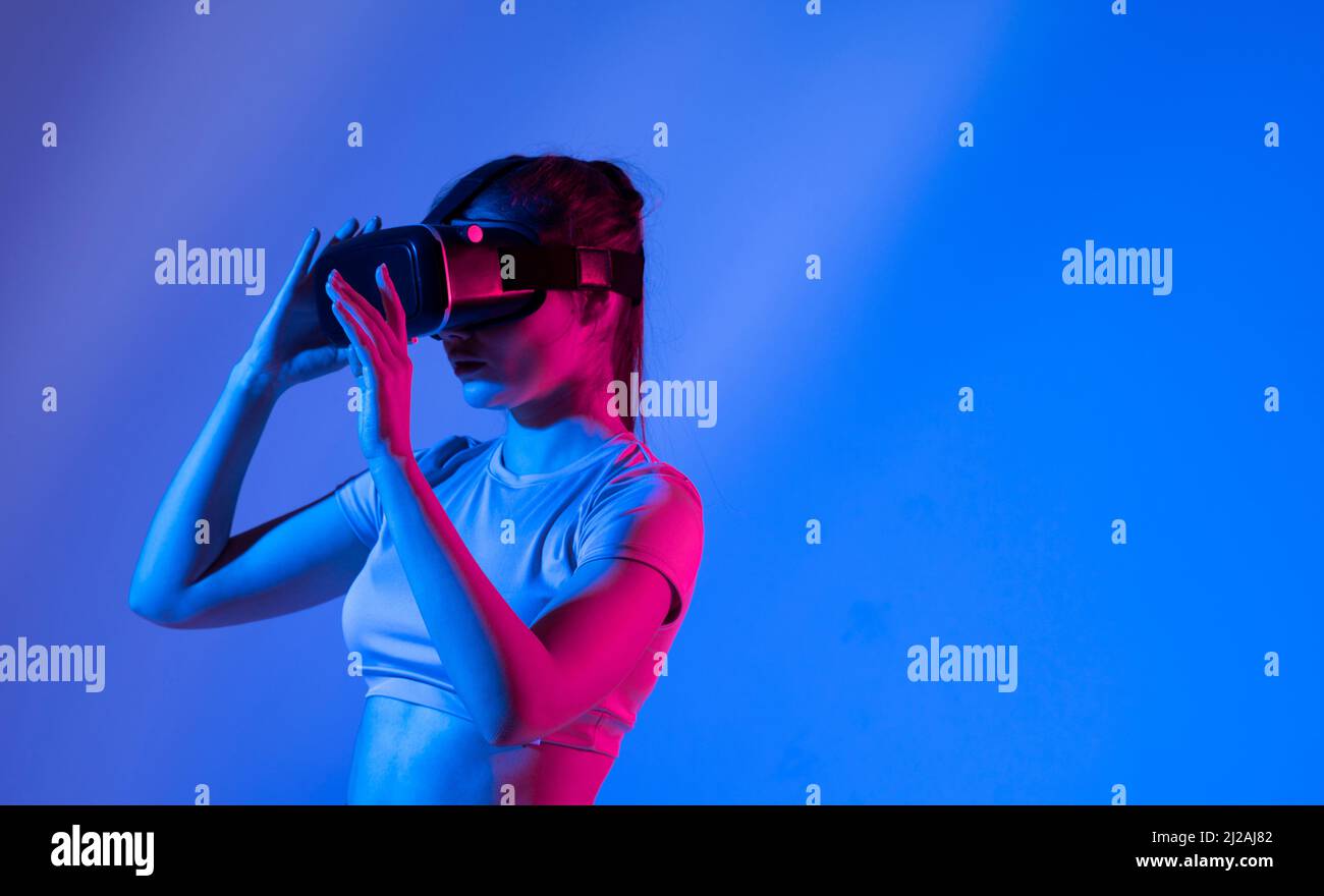 Femme qui fait l'expérience de lunettes de réalité virtuelle à la lumière du néon. Banque D'Images