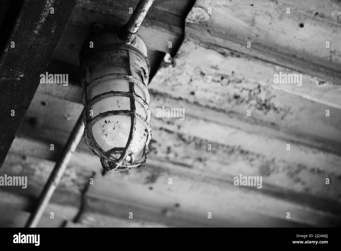 Vieux feu de travail sale et corrodé suspendu à un plafond brut. Banque D'Images