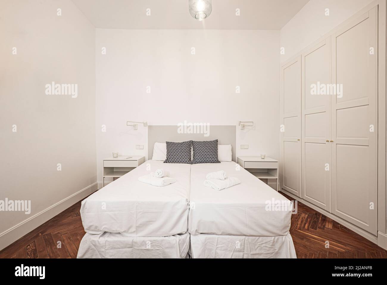 Chambre avec tête de lit en bois gris, armoire en bois blanc intégrée à quatre portes et parquet en pin à chevrons Banque D'Images