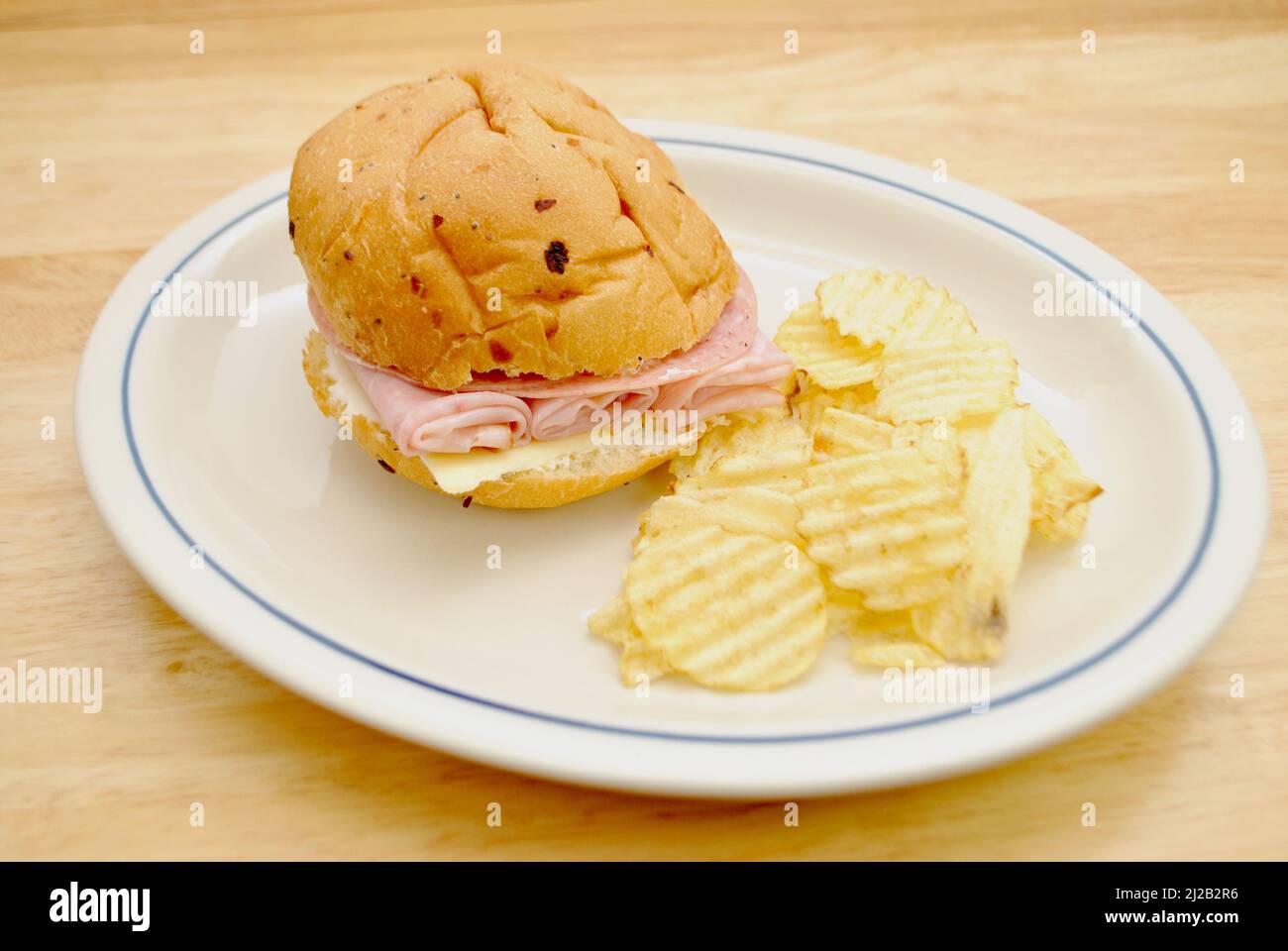 Sandwich au jambon avec fromage, mayonnaise et salami dur avec un côté de croustilles Wavy Banque D'Images