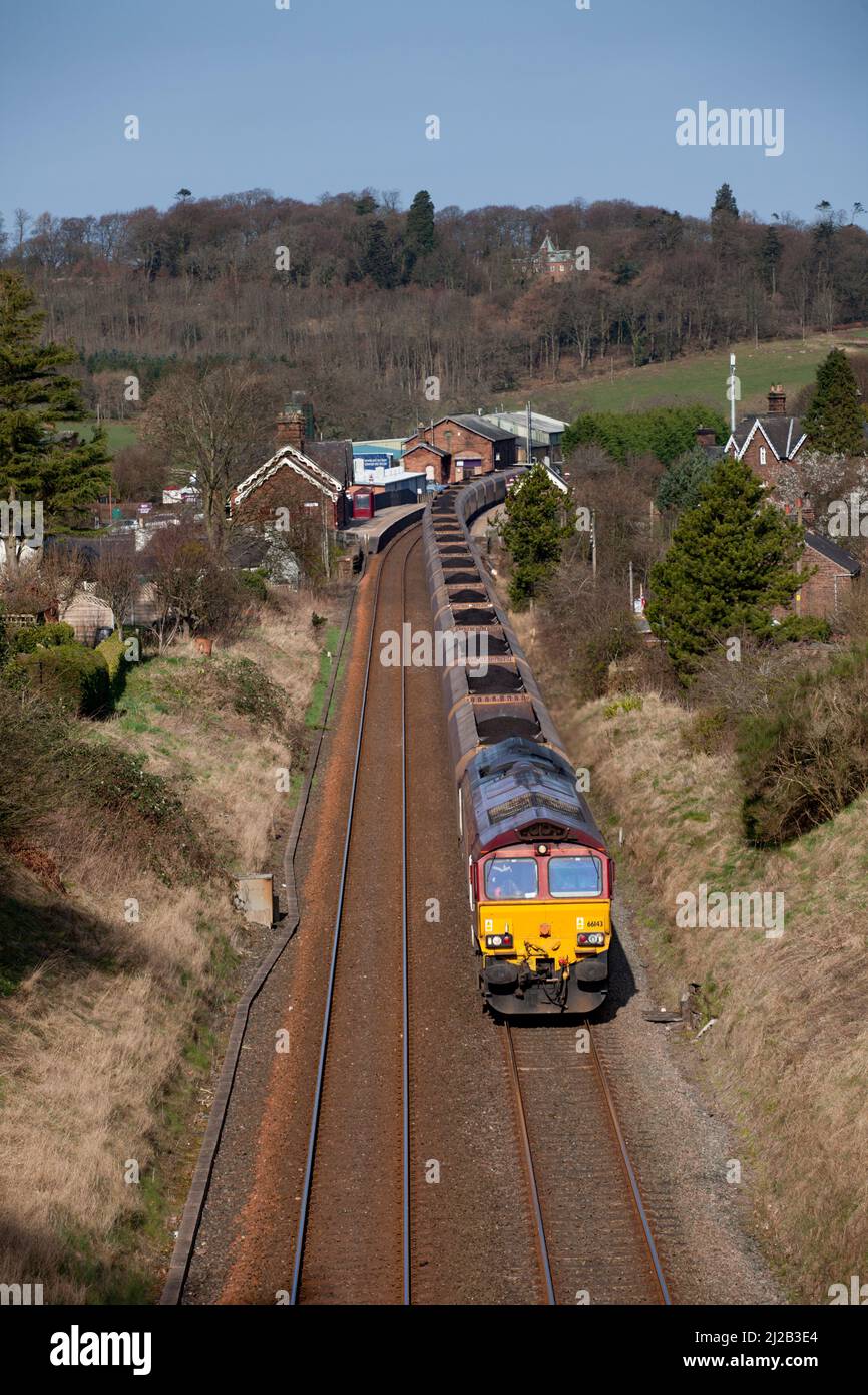 DB Schenker classe 66 diesel locomotive 66143 dans la décoration EWS en passant par Lazonby et la gare de Kirkoswald avec un train de charbon rond de merry Go Banque D'Images