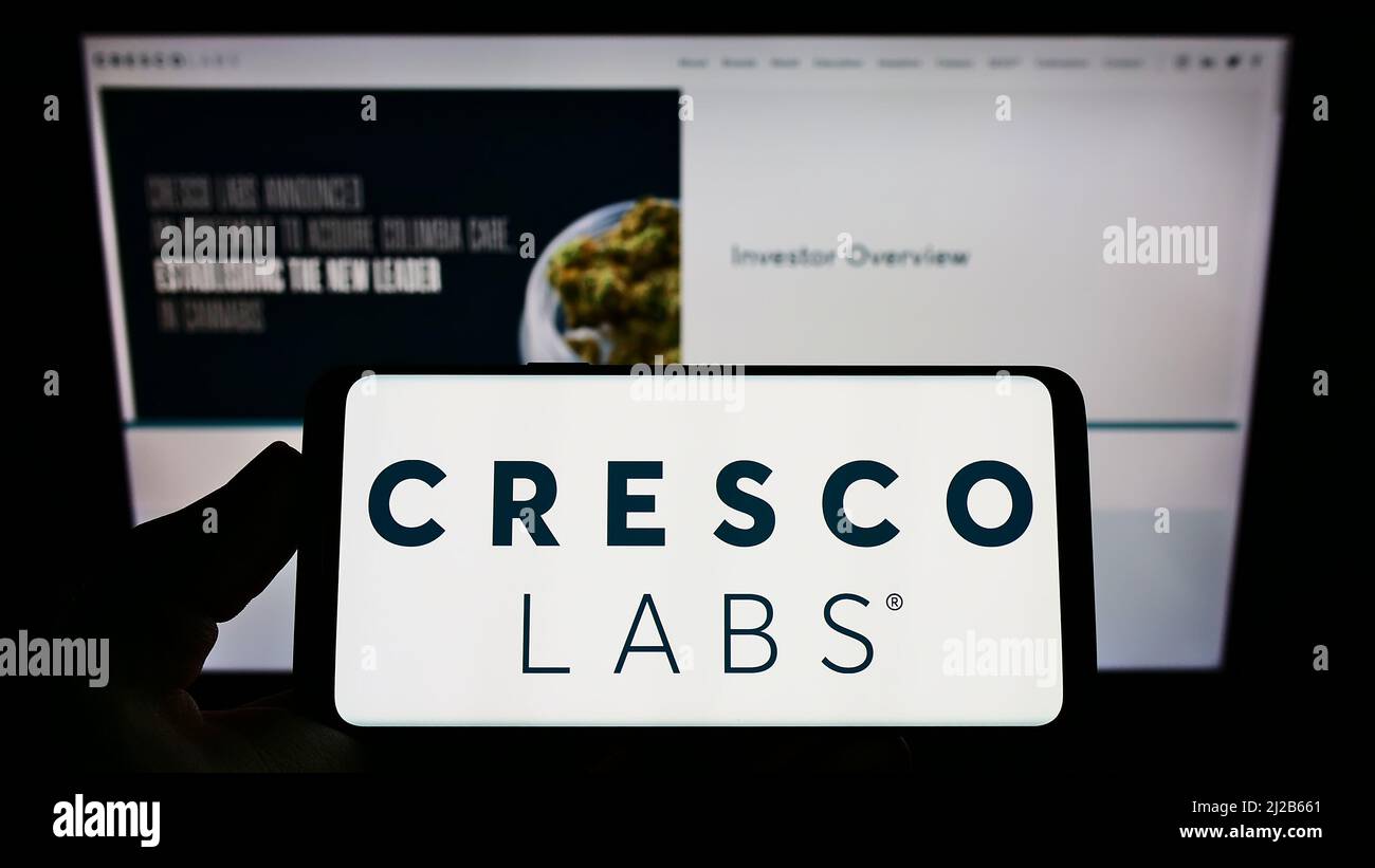 Personne tenant un smartphone avec le logo de la société américaine de cannabis Cresco Labs Inc. À l'écran devant le site Web. Mise au point sur l'affichage du téléphone. Banque D'Images