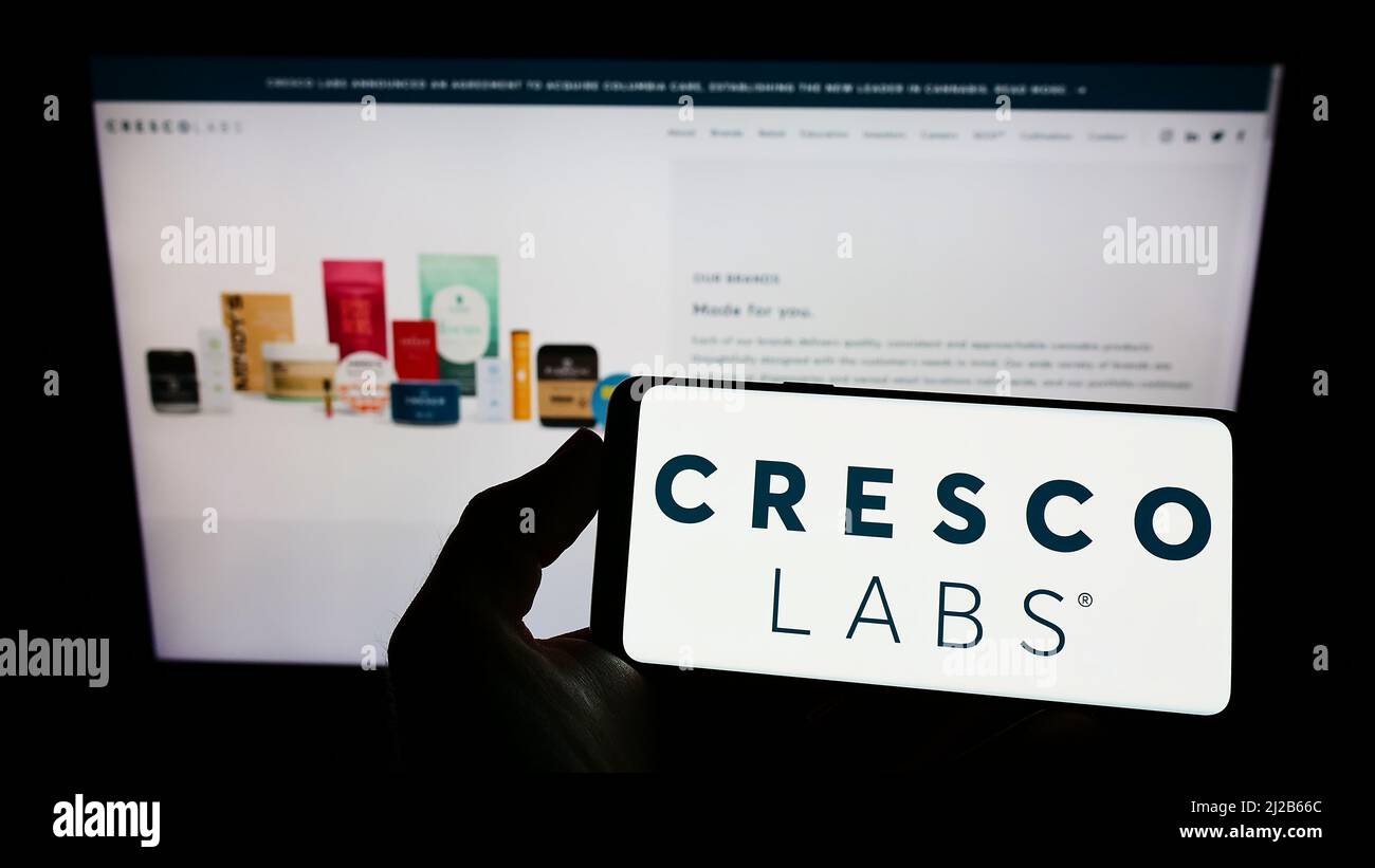 Personne tenant un téléphone portable avec le logo de la société américaine de cannabis Cresco Labs Inc. À l'écran en face de la page Web d'affaires. Mise au point sur l'affichage du téléphone. Banque D'Images
