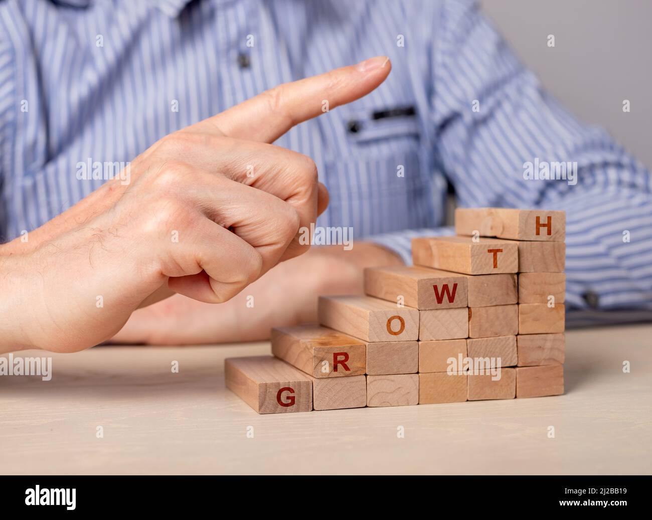 Échelle de carrière à partir de blocs de bois avec la croissance de mot. Concept de développement professionnel. Main d'homme d'affaires pointant vers le haut de l'escalier. Réalisation des objectifs. Photo de haute qualité Banque D'Images