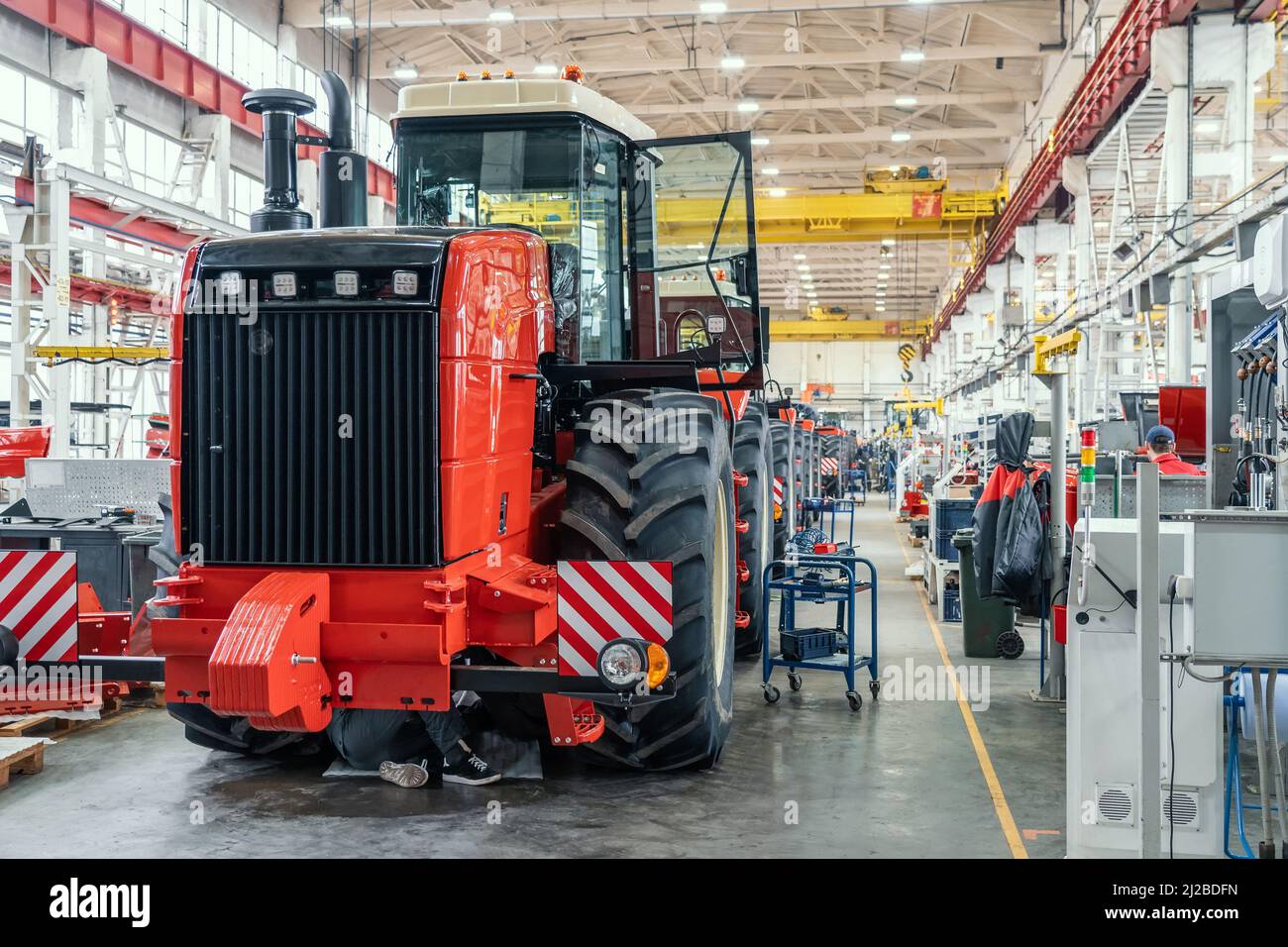 Gros tracteur ou moissonneuse rouge en cours d'assemblage en usine sur la chaîne de production pour la fabrication de machines agricoles. Banque D'Images