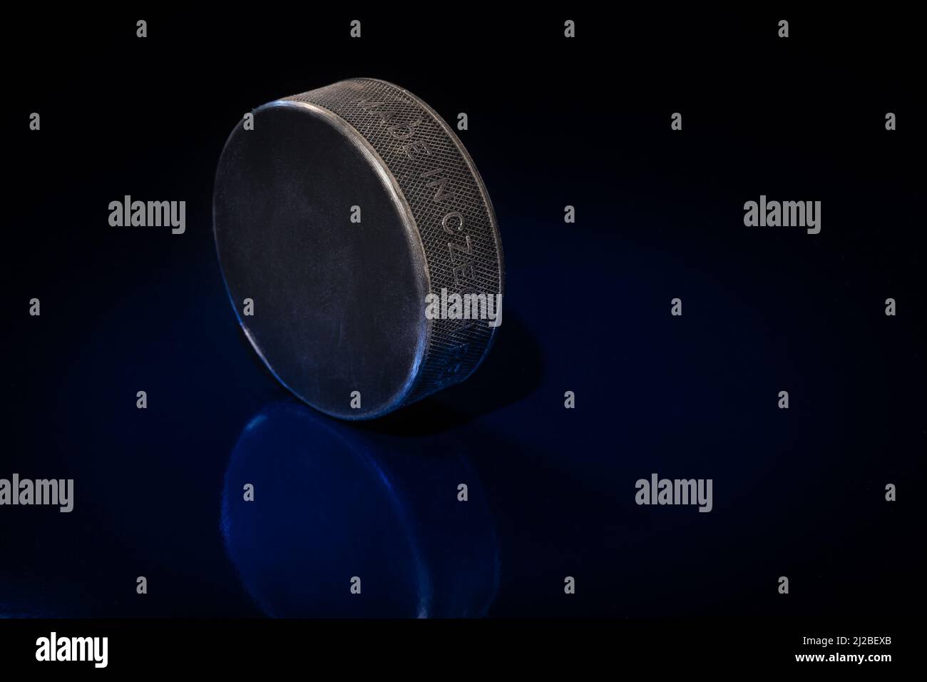 Helsinki / Finlande - 31 MARS 2022 : gros plan d'un palet de hockey sur glace noir sur fond bleu. Banque D'Images