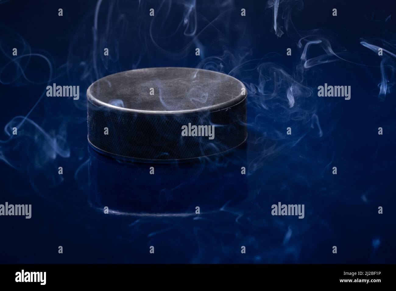 Helsinki / Finlande - 31 MARS 2022 : gros plan d'un palet de hockey sur glace noir sur fond bleu. Banque D'Images