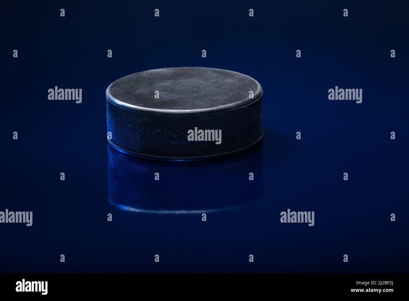 Helsinki / Finlande - 31 MARS 2022 : gros plan d'un palet de hockey sur glace noir sur fond bleu. Banque D'Images