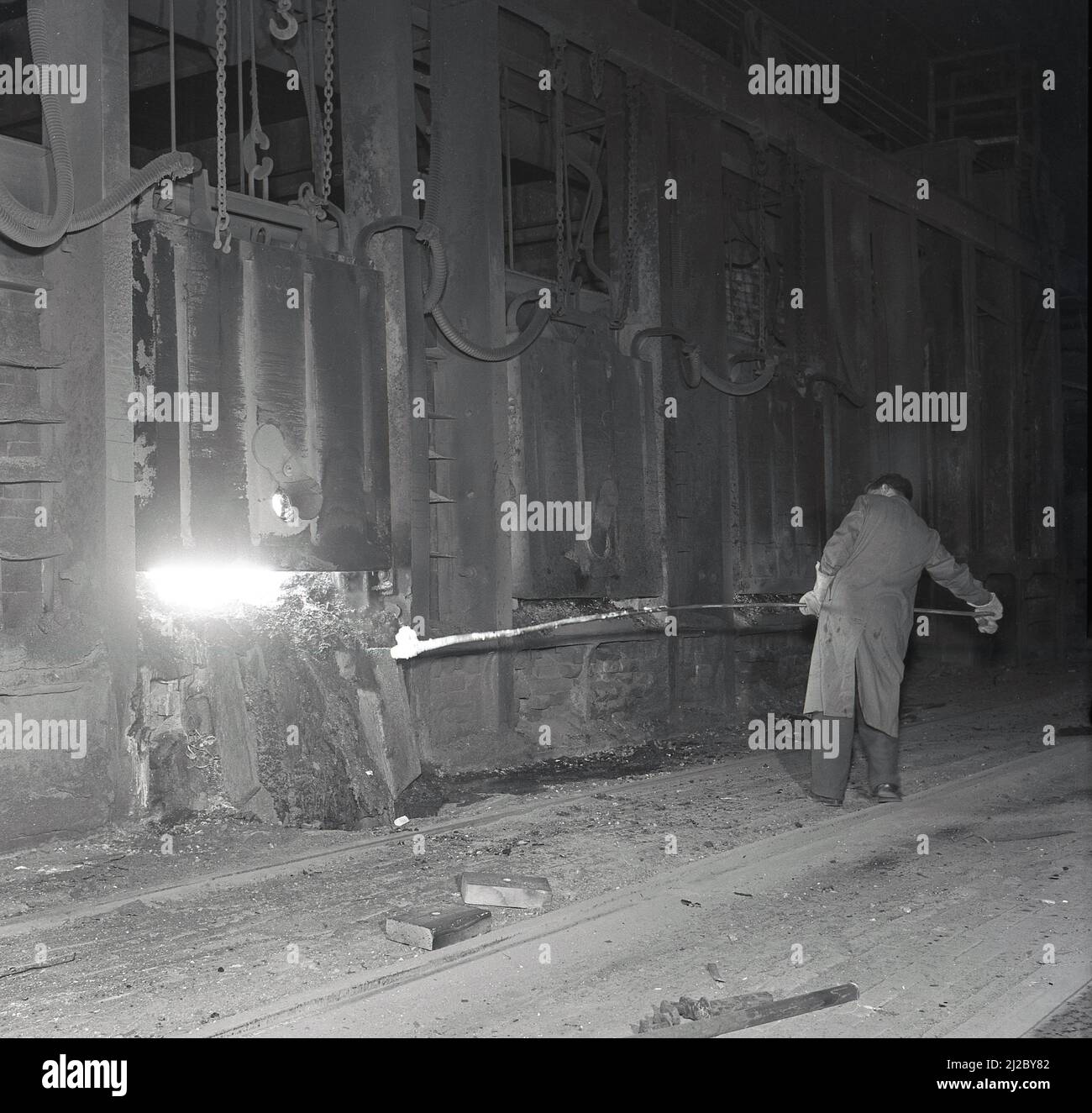 1955, historique, un ouvrier de l'acier avec un long poteau lourd dans un four à foyer ouvert à l'usine d'acier d'Abbey Works, Port Talbot, pays de Galles, Royaume-Uni, maison de la compagnie de l'acier du pays de Galles. Banque D'Images