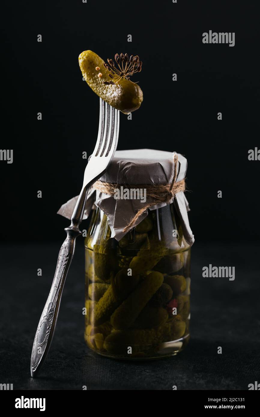 Cornichons, concombre mariné sur une fourchette, pot en verre avec légumes marinés Banque D'Images