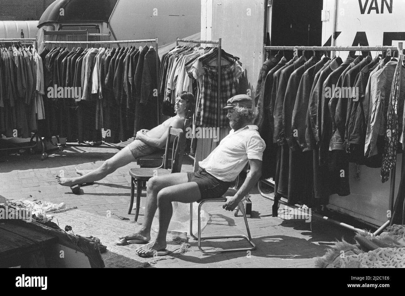 Chaleur à Amsterdam, vendeurs de vêtements d'hiver bains de soleil sur Waterlooplein ca. 8 juin 1976 Banque D'Images