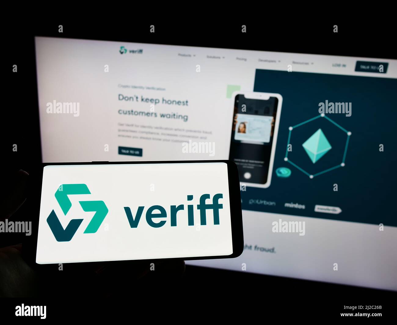Personne tenant un téléphone portable avec le logo de la société estonienne de vérification de l'identité Veriff à l'écran en face de la page Web. Mise au point sur l'affichage du téléphone. Banque D'Images