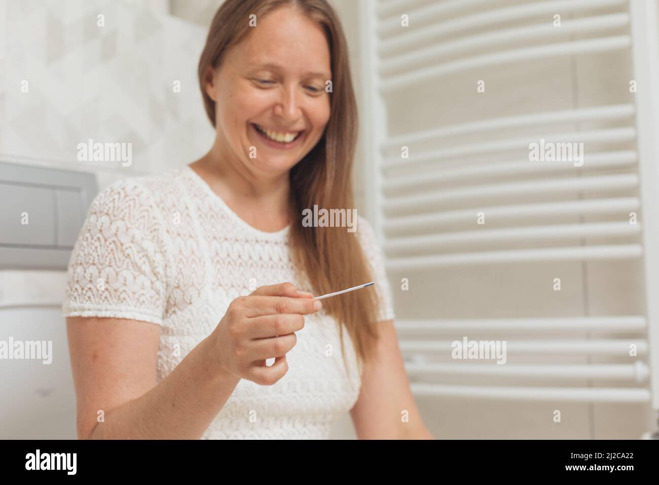 Bonne femme d'âge moyen avec test de grossesse dans les toilettes Banque D'Images