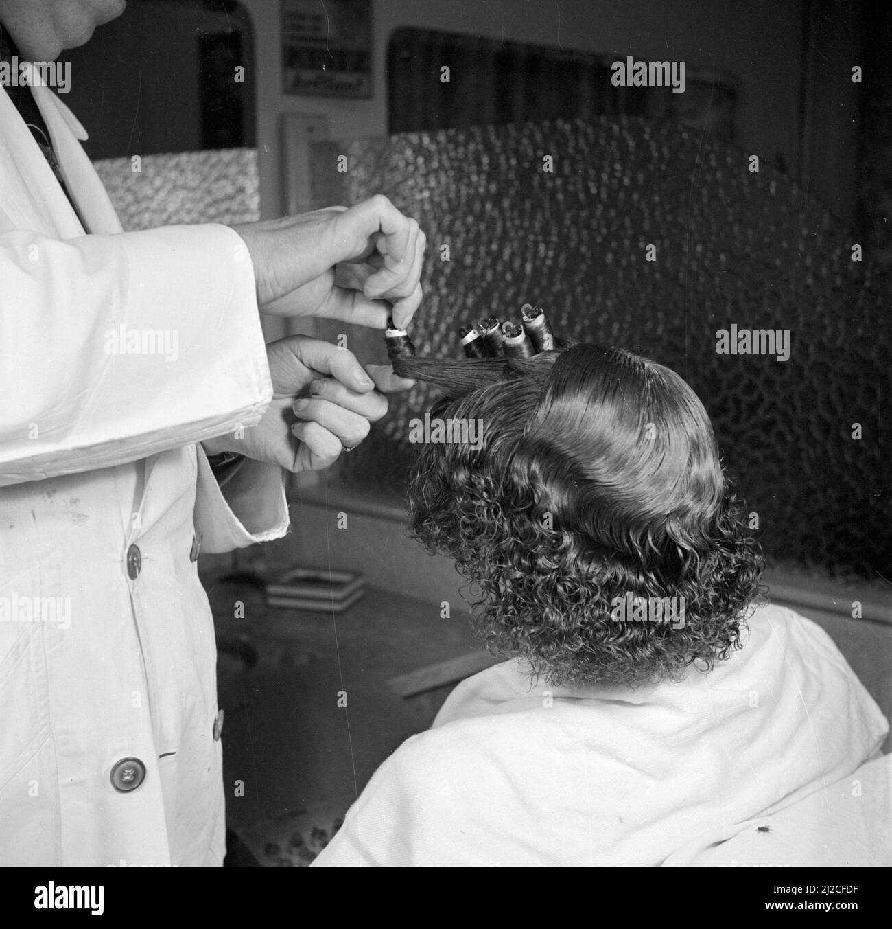 Femme assise dans une chaise dans un salon de coiffure ou salon de beauté ca. 1950 Banque D'Images