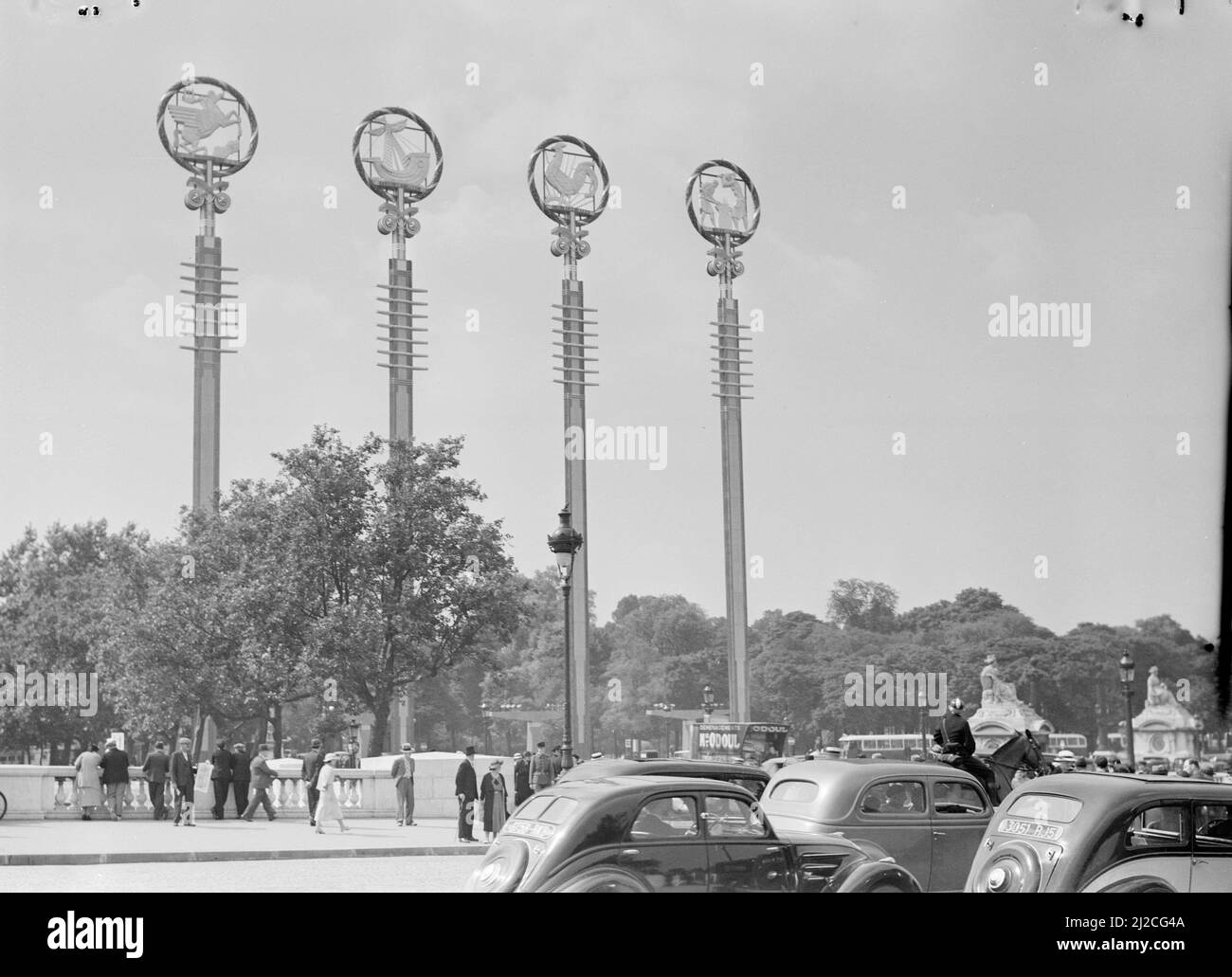 Quatre mâts avec des symboles aux pavillons français, avec le public, la circulation automobile, y compris une camionnette, et un policier à cheval ca: 1937 Banque D'Images