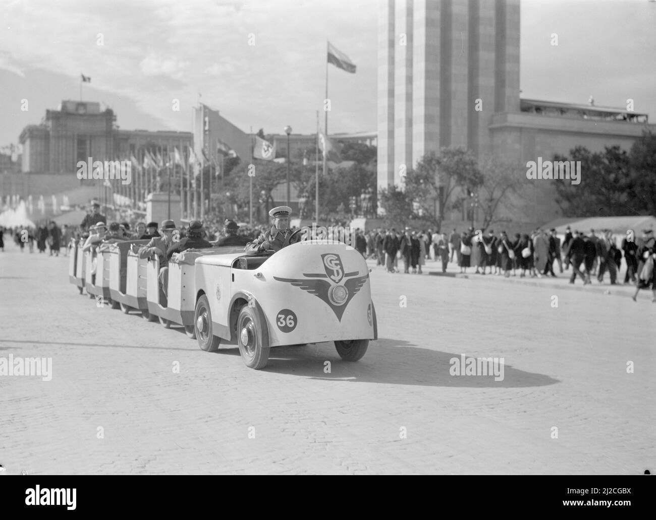Petit train dans le parc des expositions avec vue sur le Palais de Chaillot , l'avant du pavillon allemand et une rangée de mâts de drapeaux ca: 1937 Banque D'Images