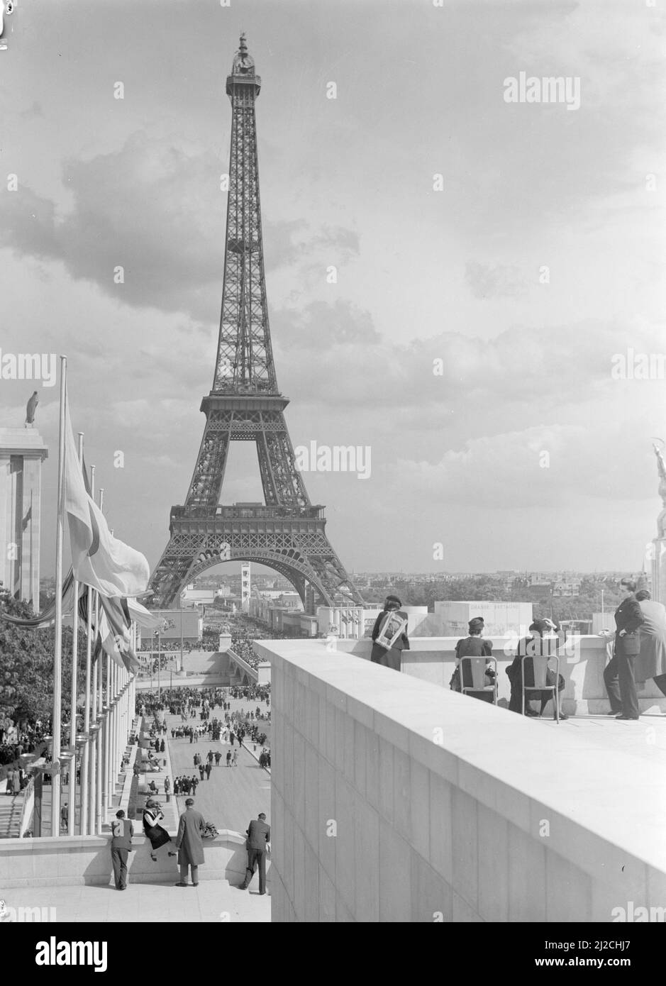 Vue depuis les terrasses du Palais de Chaillot de la Tour Eiffel, avec les pavillons allemand et belge à gauche et le pavillon de Suède à droite et avec un public en premier plan, quelques personnes sur les chaises environ: 1937 Banque D'Images