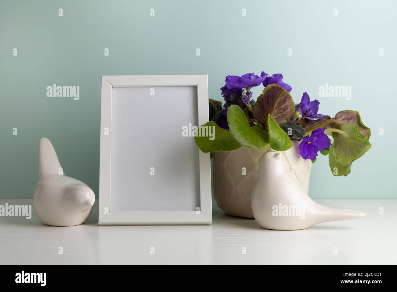 Table de bureau confortable avec deux oiseaux en céramique, un cadre photo et une fleur dans un pot. Hygge, style boho, salon scandinave Banque D'Images