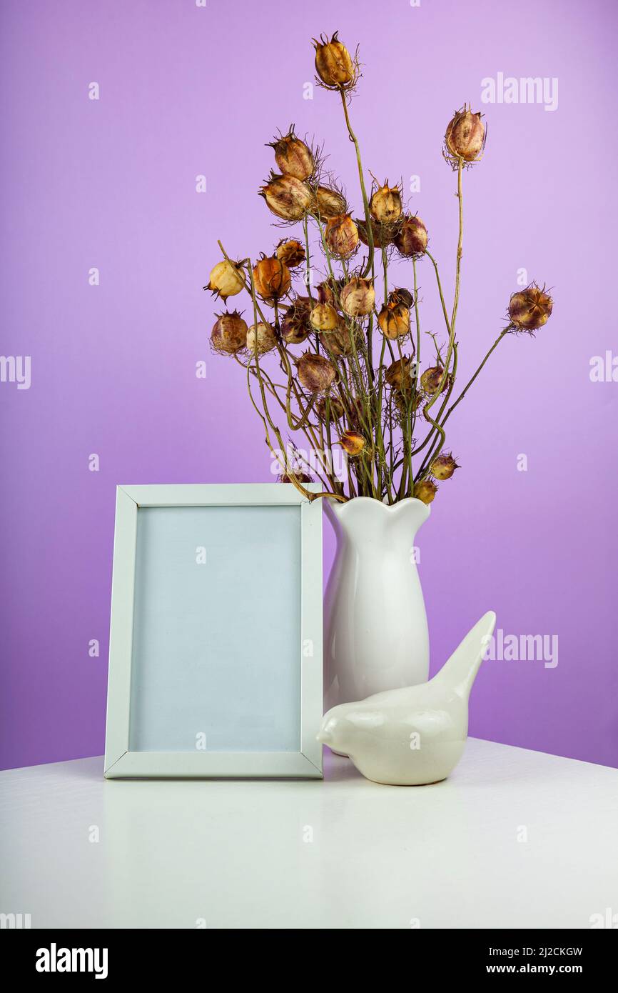 Table de bureau confortable avec vase avec fleurs sèches, oiseau en céramique et cadre photo. Hygge, style boho, salon scandinave. Banque D'Images