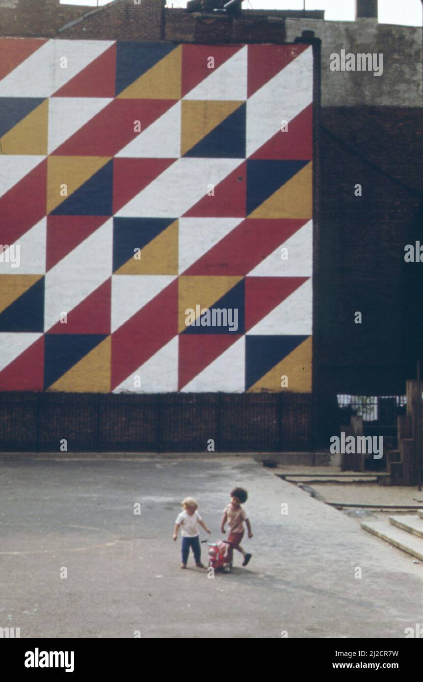 Enfants jouant sous une fresque accrocheuse dans un petit parc de la ville, à l'angle de 29th Street et second Avenue dans Eastside Manhattan. C'est un bon exemple d'un parc non-vert joliment conçu ca. 1973 Banque D'Images