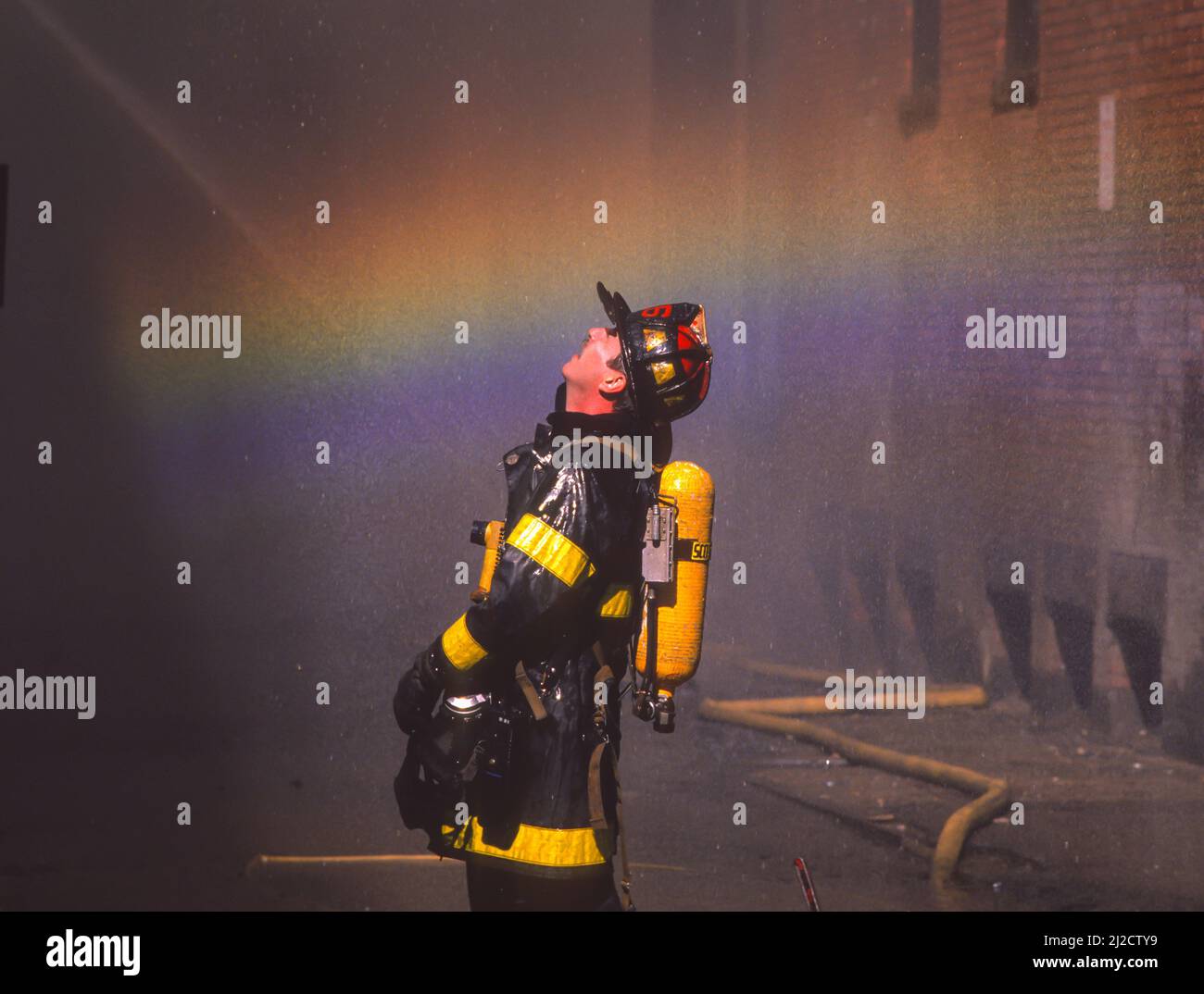 BOSTON, MASSACHUSETTS, États-Unis - le pompier de Boston regarde le bâtiment pendant le feu, avec l'arc-en-ciel. Banque D'Images