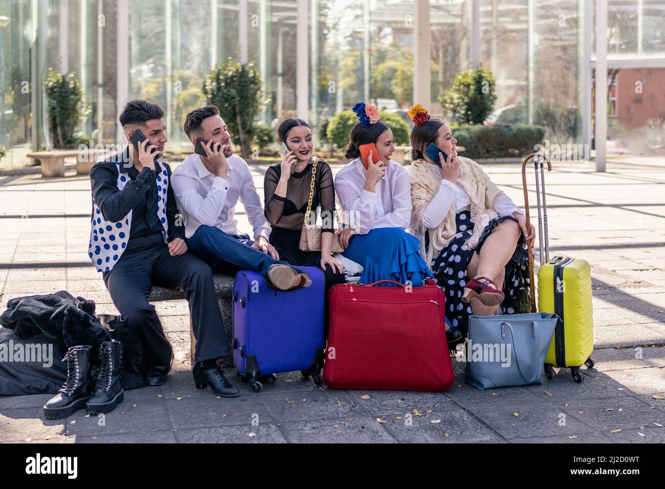 groupe de jeunes danseurs de flamenco assis sur un banc parlant sur un téléphone portable Banque D'Images
