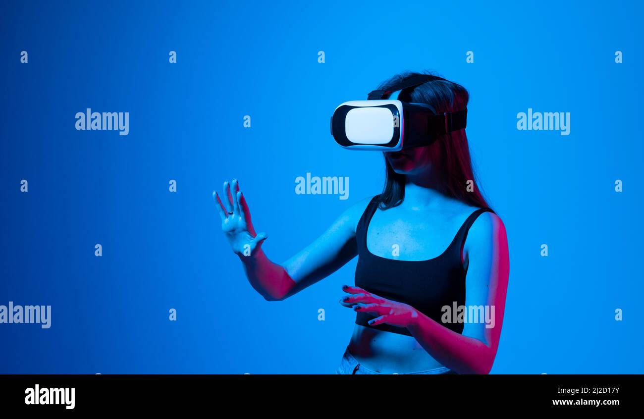 Une femme stupéfait d'avoir une expérience en utilisant des lunettes de réalité virtuelle et en explorant un monde virtuel. Une fille passe son temps en métaverse tout en se traînant Banque D'Images