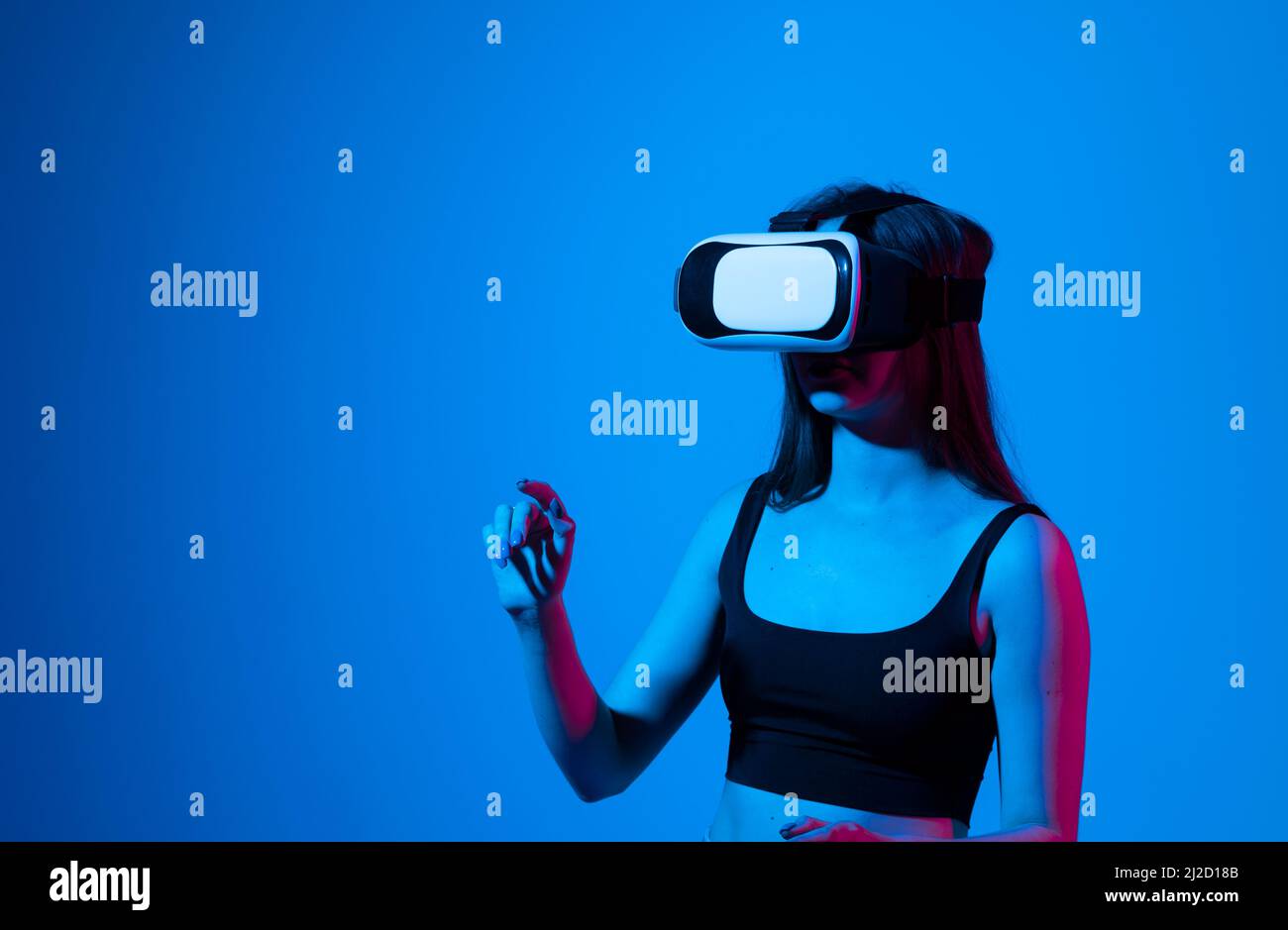 Portrait d'une jeune femme jouant dans des VR-lunettes à la lumière du néon sur fond bleu.Concept gadgets et technologies modernes.Concept technologique futur Banque D'Images