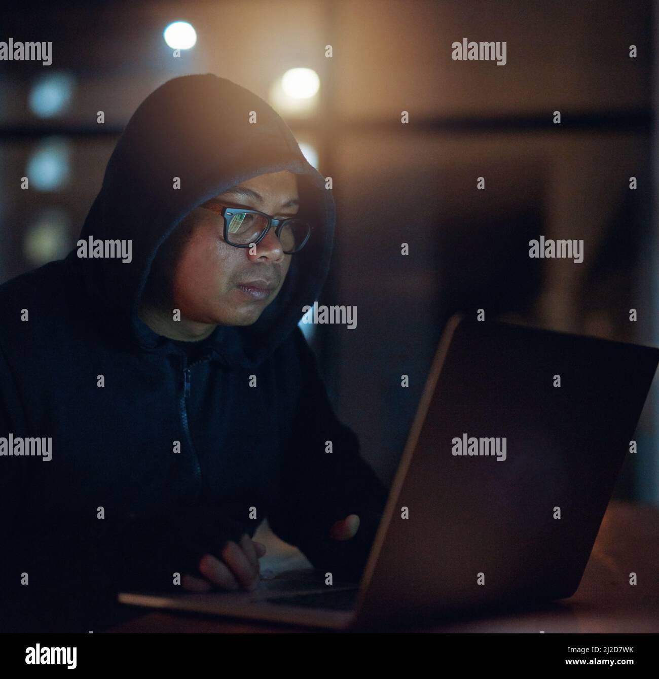 Il peut se fissurer dans n'importe quel système. Photo d'un pirate utilisant un ordinateur portable dans l'obscurité. Banque D'Images