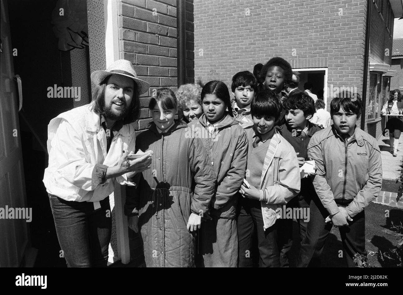 Dave Hill, star du slade, a essayé de ne pas « faire tomber la maison » lorsqu'il a fait une visite de retour après 20 ans dans son vieux lieu de travail. Il ouvrait deux maisons de spectacle pour un développement de 67 bâtiments à Heathcroft, Wolverhampton pour Tarmac Houses (Midlands). Il était un acheteur stagiaire pour Tarmac à l'âge de 18 ans, avant de tirer à la stardom. Des enfants de l'école junior de farandole étaient sur place pour voir Dave couper le ruban - ils ont suivi le développement et l'histoire du site comme un projet scolaire. 12th juin 1985. Banque D'Images