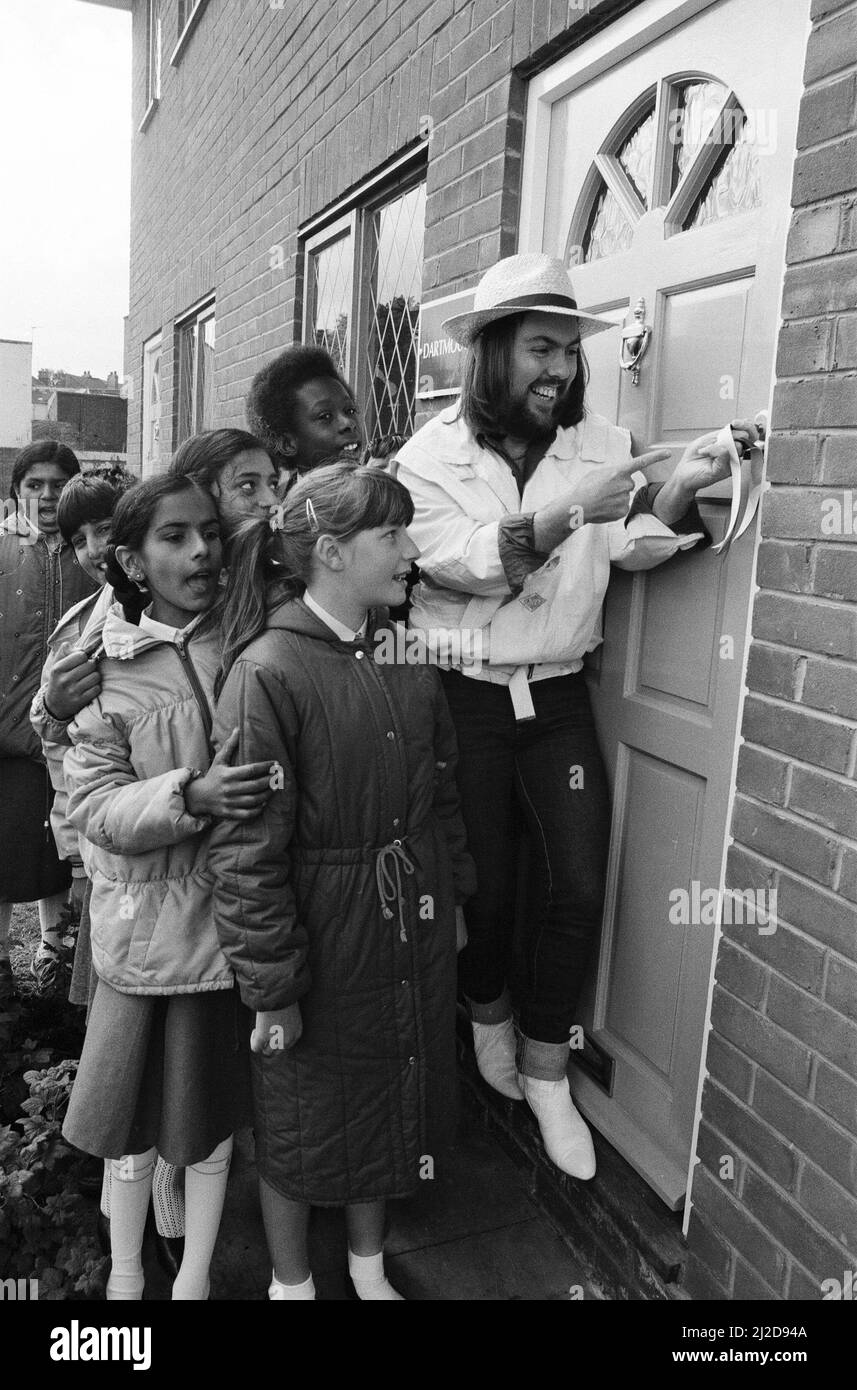 Dave Hill, star du slade, a essayé de ne pas « faire tomber la maison » lorsqu'il a fait une visite de retour après 20 ans dans son vieux lieu de travail. Il ouvrait deux maisons de spectacle pour un développement de 67 bâtiments à Heathcroft, Wolverhampton pour Tarmac Houses (Midlands). Il était un acheteur stagiaire pour Tarmac à l'âge de 18 ans, avant de tirer à la stardom. Des enfants de l'école junior de farandole étaient sur place pour voir Dave couper le ruban - ils ont suivi le développement et l'histoire du site comme un projet scolaire. 12th juin 1985. Banque D'Images