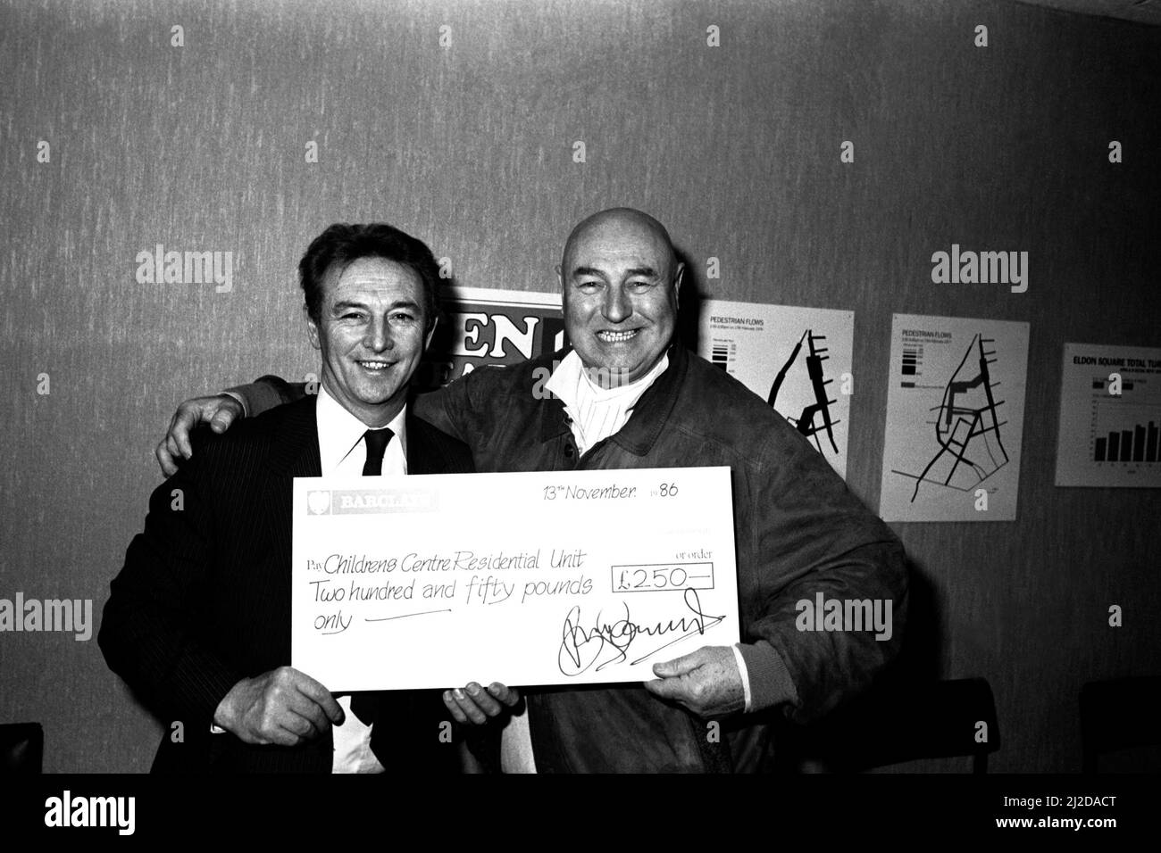 L'acteur Bill Maynard, qui porte une tête rasée pour son rôle de Daddy Warbucks dans la comédie musicale Annie à l'Empire Sunderland, a donné le signal d'une activation informatisée des lumières de Noël dans le centre commercial Eldon Square à Newcastle 13 novembre 1986 - Bill photographié Directeur du centre Gordon Allanson, Gordon a présenté à Bill un chèque de 250 ¿pour organisme de bienfaisance au lieu de frais pour la mise en marche. Banque D'Images