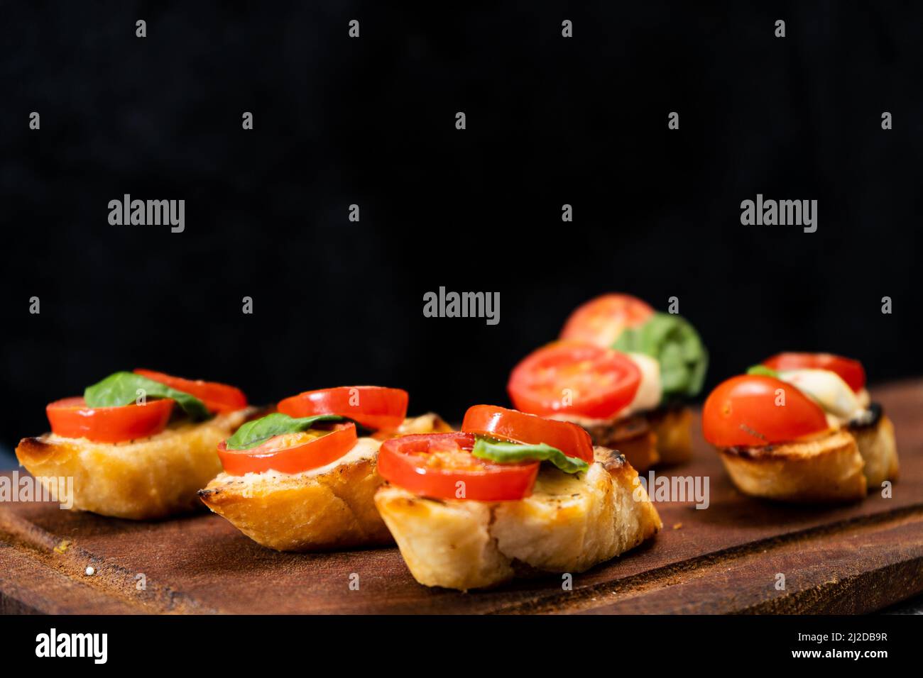 Bruschetta typiquement italienne ou tapa espagnol avec tomates cerises, basilic et fromage à tartiner de type Philadelphie. Concept alimentaire méditerranéen. Copier l'espace. Banque D'Images