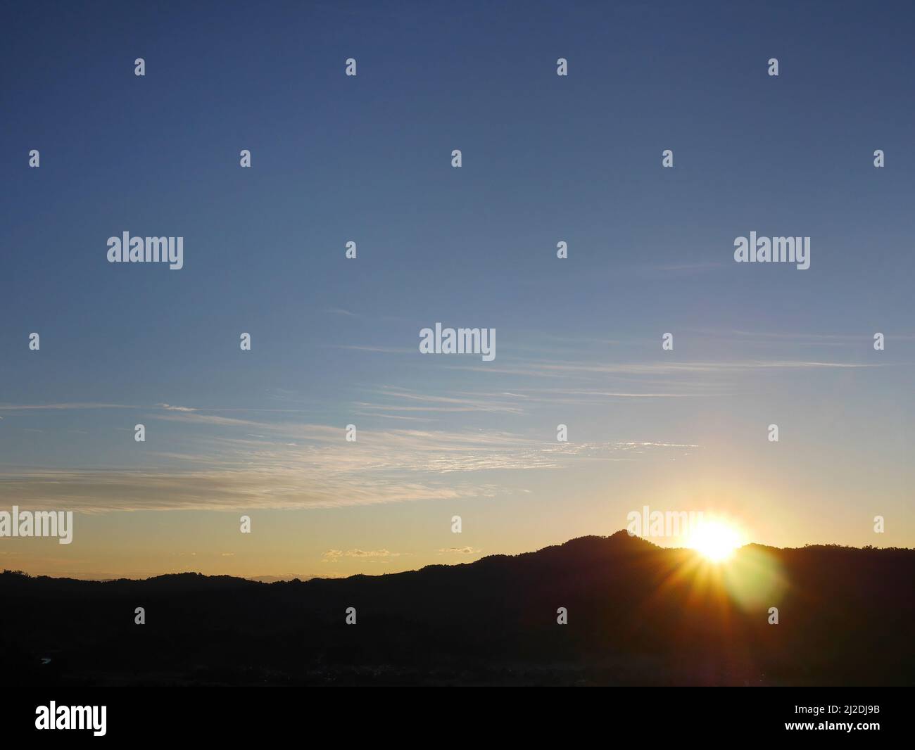 Magnifiques lumières solaires avec silhouette montagne sombre ombre et ciel bleu Banque D'Images
